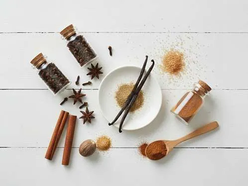 Různé koření na švestkový koláč: mletá skořice, hřebíček, cukr a vanilka připravené k pečení.
