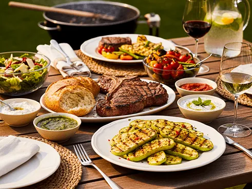 Různé grilované jídlo na stole. Maso zelenina, pečivo.