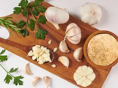 Čerstvý a granulovaný česnek na prkýnku.